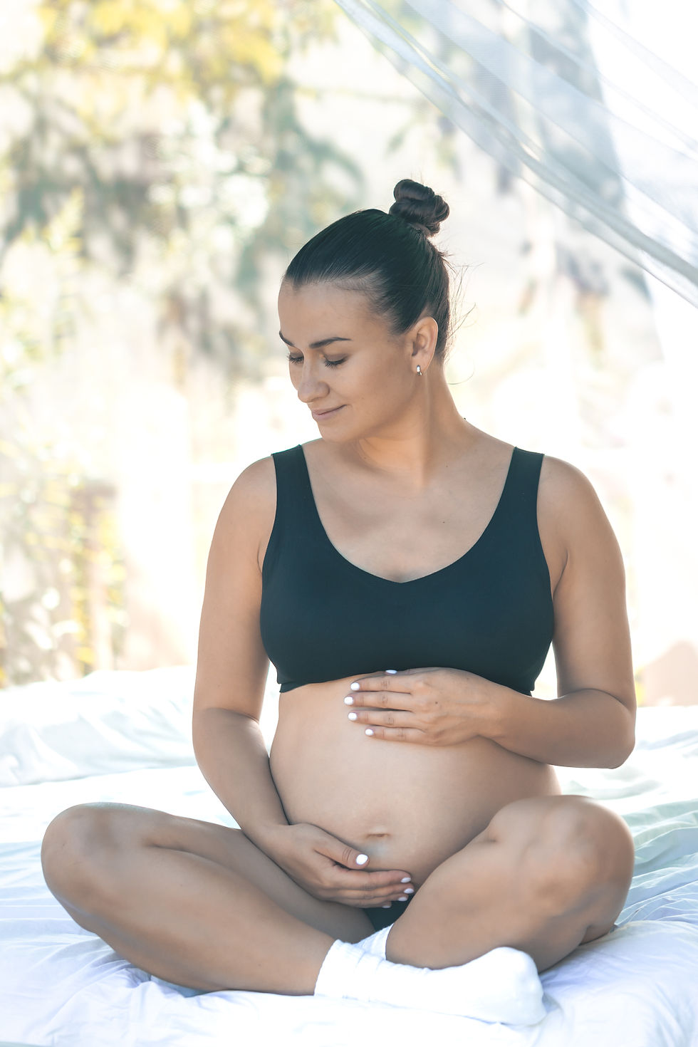 happy-pregnant-woman-touching-her-belly-while-sitting-white-bed.jpg