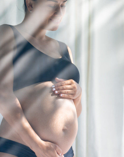 pregnant-woman-carrying-her-large-belly-while-standing-by-window.jpg