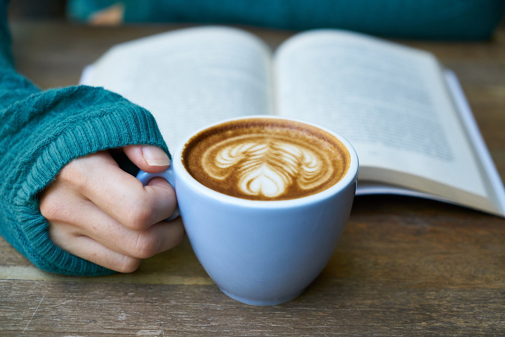 Hygge image of a cozy warm mug of coffee while reading a book
