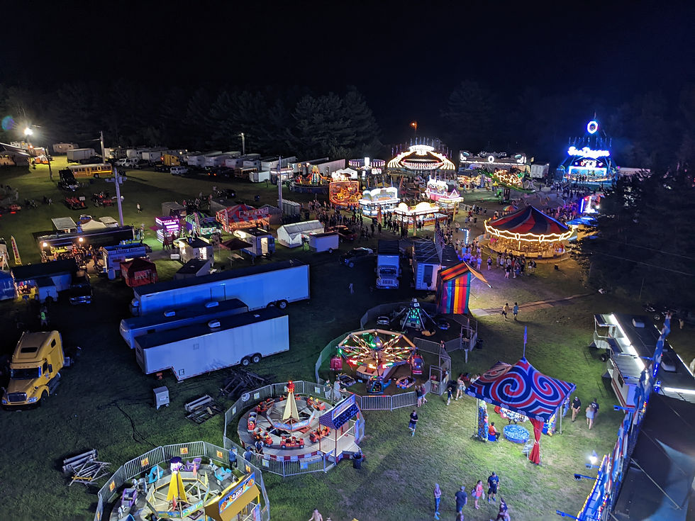 Rides and trailers lit up on grass field