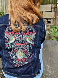 Green, red, white and light blue threads are embroidered into an intricate pattern.