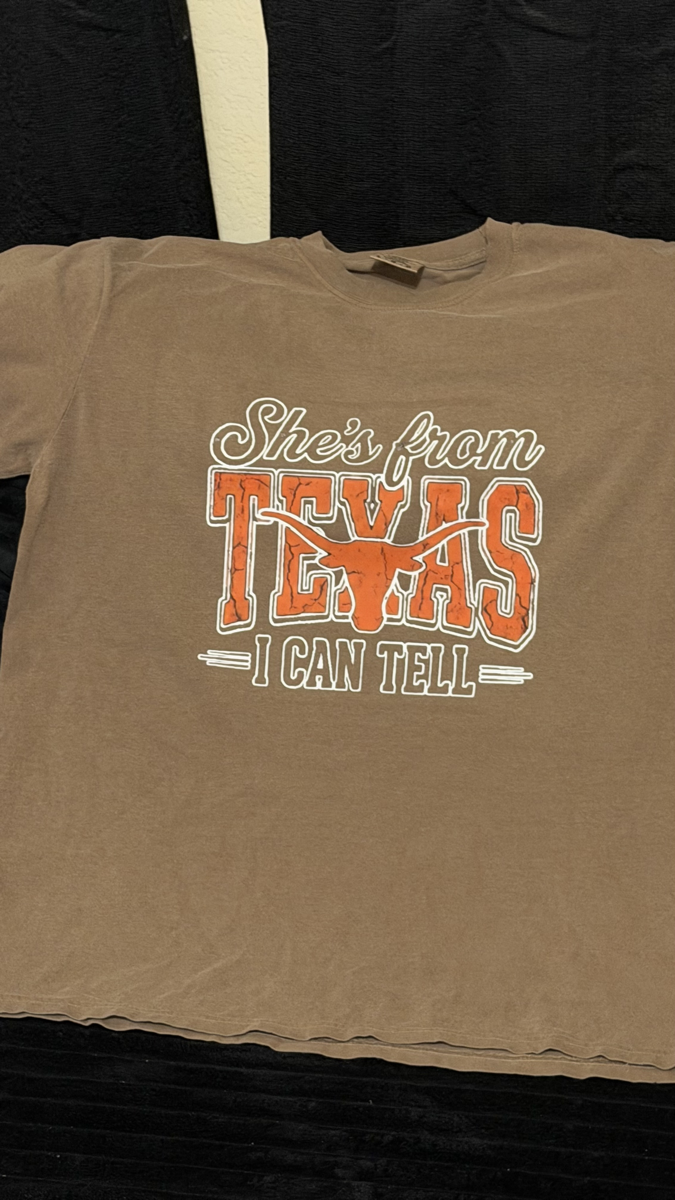 Custom order — a brown tee reading “She's from Texas, I can tell” in orange and white