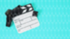 Turquoise blue background with video production clapperboard on top of a roll of video film.