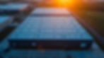 Large industrial building with vast flat roof under orange sunset.