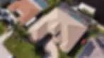 Aerial view of a house with a brown tile roof, pool, and driveway.