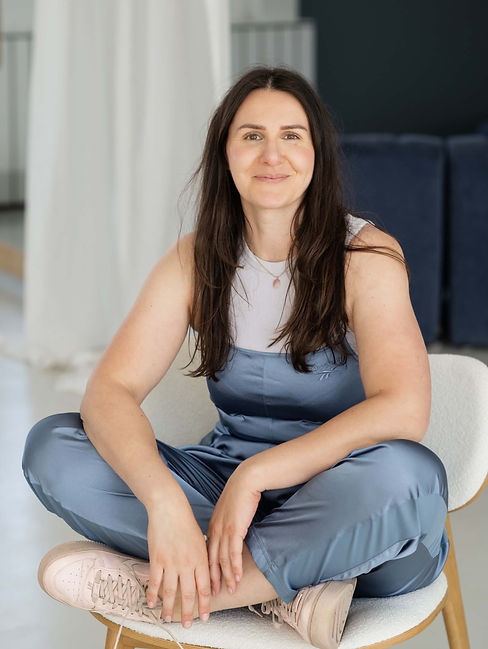 Evi Gulich, verloskundige en coach zit ontspannen en vriendelijk kijkend op een stoel