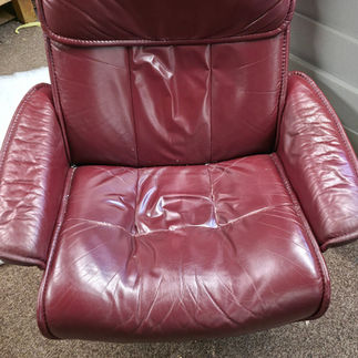 Worn and faded burgundy leather armchair seat before professional restoration