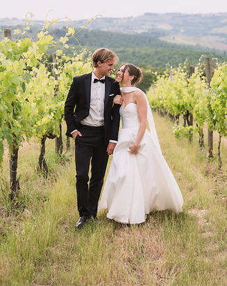 koppel loopt door de wijngaard tijdens een golden hour shoot in toscane en lacht naar elkaar