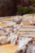 multiple salt ponds at different evaporation levels. the walls between the terraces are encrusted with salt.