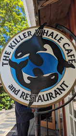 A round wooden sign advertising the Killer Whale Cafe and Restaurant