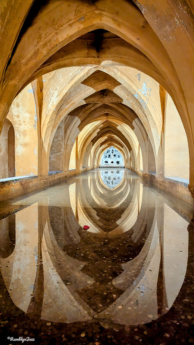 a  long pool of water reflecting the arched walls and ceiling