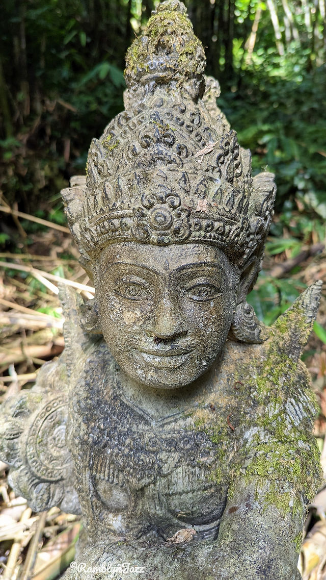 A stone statue of a Balinese fgurre with an ornate headpiece