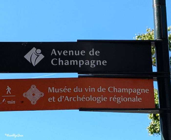 Street signs for Avenue de Champagne and Musée du vin de Champagne et d’Archéologie régionale against a clear blue sky.