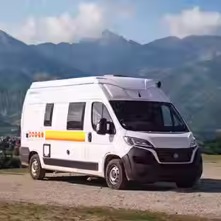 A white campervan with yellow and orange stripes against a mountain background.