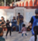 A man playing a saxophone with children dancing in front of him