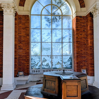 Wooden octagonal memorial pedestal in a brick-arched hall before a frosted window etched with 1940 and Dunkirk 1940.