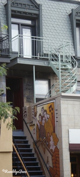a residential building with a spiral staircase and a mural at street level