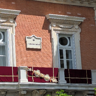 A balcony decorated for Easter with a deep red velvet drape adorned with palm