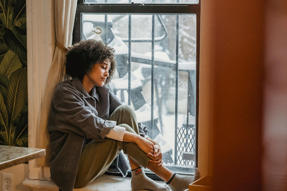 A woman sitting in a windowsill with snow outside.