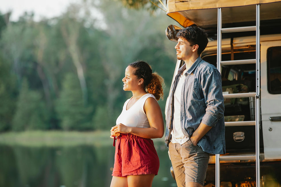Two people standing behind their vehicle, staring at the sunset over a large body of water. Things are going well, but trauma responses may still linger underneath.