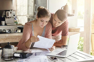 Young couple reviewing mortgage paperwork while planning to buy their first home in Bend, Oregon.
