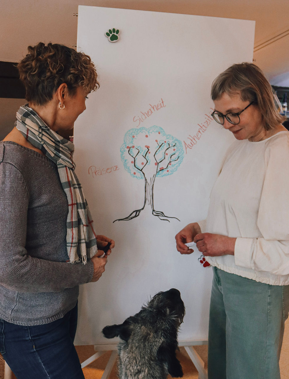 Zwei Menschen mit Hund vor einem Whiteboard