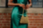 Fashion editorial branding featuring a green satin dress and gold bag.