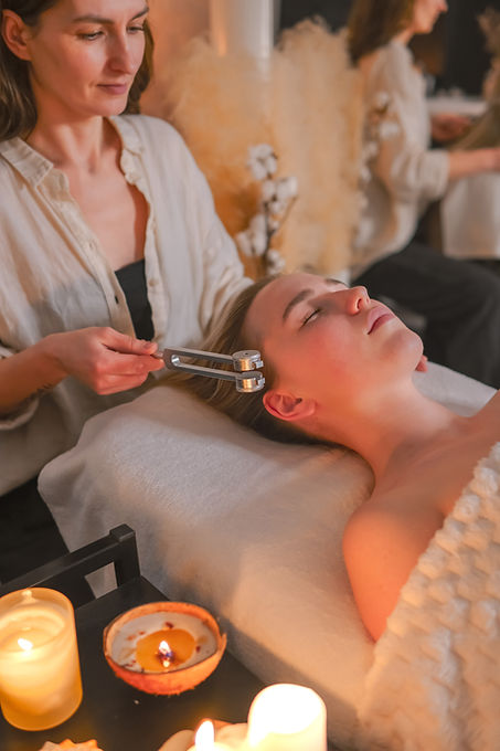 Facial massage and tuning fork sound therapy in candlelit spa, holistic skincare wellness