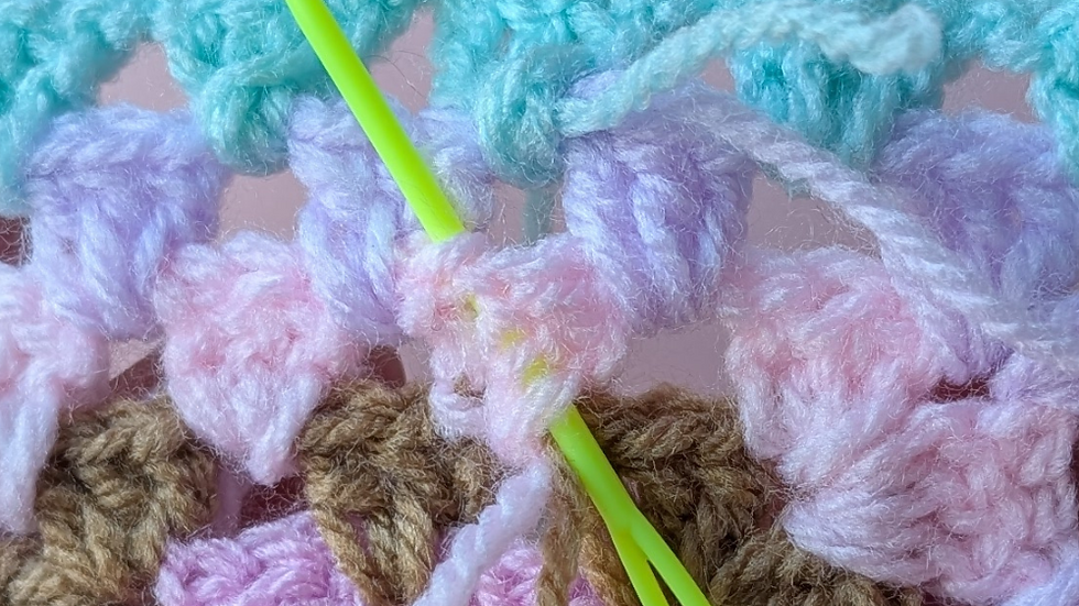 Feed your needle through the stitches diagonally