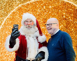 Santa Claus takes a selfie with a happy man.