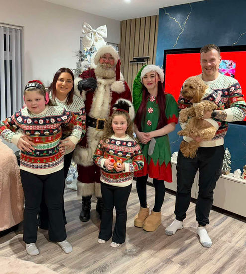 Family group with Santa, an elf, and a dog in festive sweaters