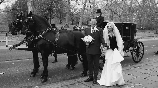 Bride and Groom stood in front of a horse and carriage