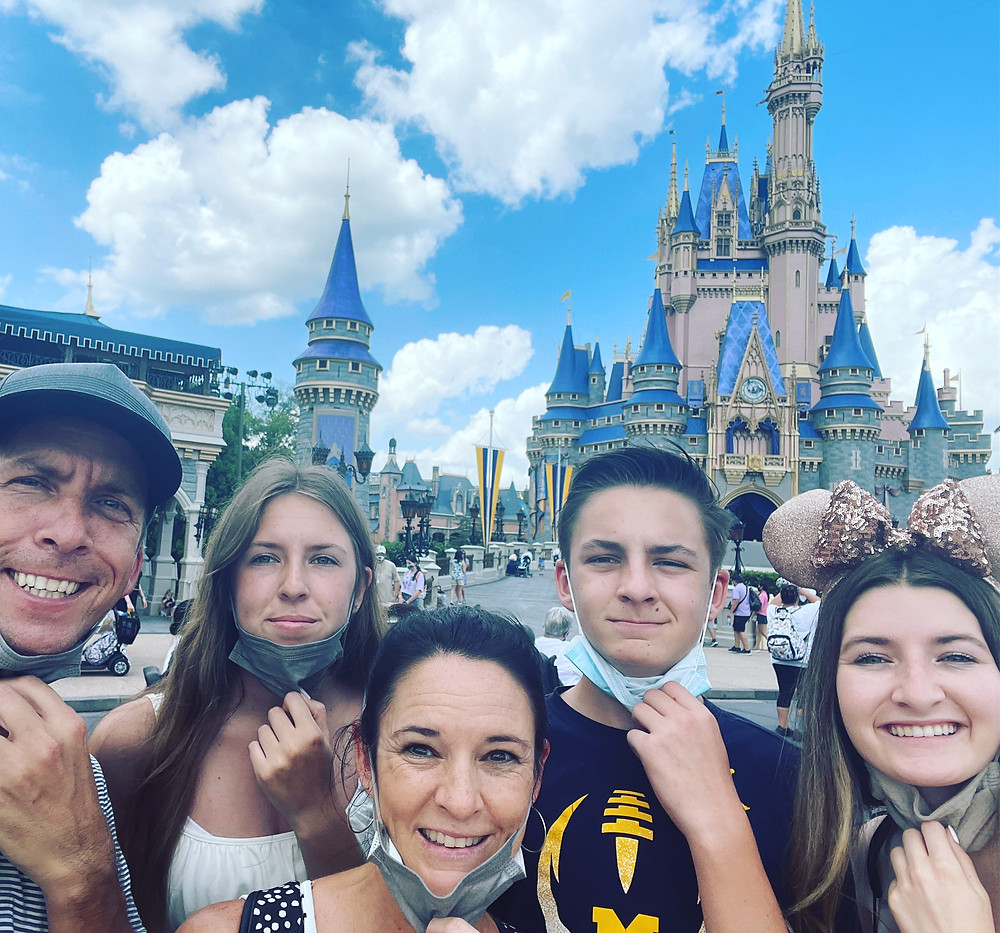Family pulling down their masks in front of Disney Castle
