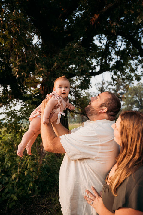 Dad lifts up baby outdoors.