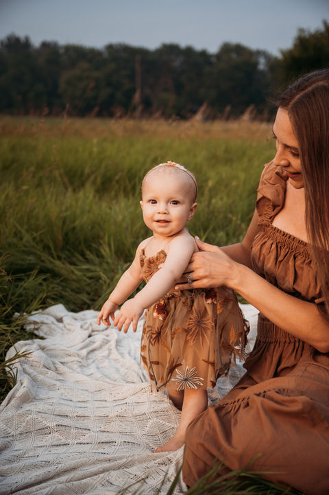 One year old in grassy field with her mom.