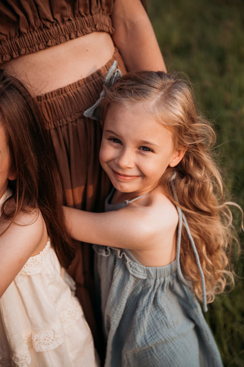 Girl hugging mom in grassy field.