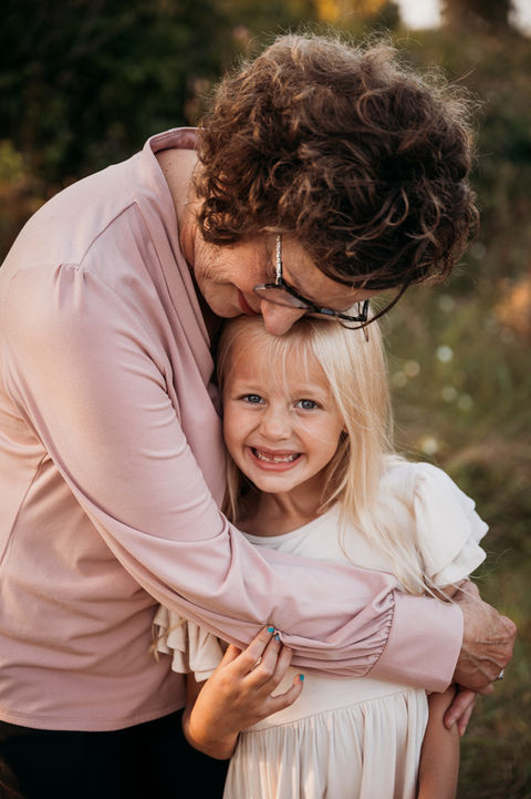 Grandma hugging granddaughter who smiles at the camera.