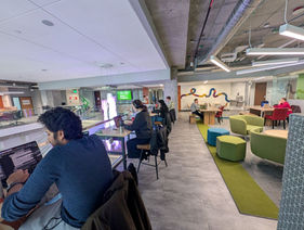 4 members working at high top tables with a lounge area in the back