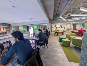 4 members working at high top tables with a lounge area in the back