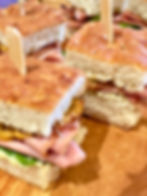 Mini Mortazza bites on focaccia. Mini Mortazza Bites with sundried tomato mayo, mascarpone with pistachio pesto and watercress. Skewered sandwiches for a Canadian party