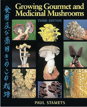 Book cover of Growing Gourmet and Medicinal Mushrooms by Paul Stamets, showing various mushroom species in a grid format on a black background with Japanese text on the left.