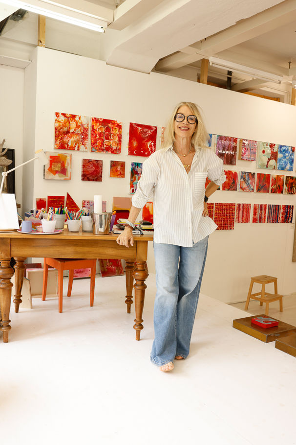 Artist in white shirt and jeans in her bright studio.