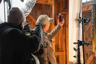 actor holding up a maple syrup bottle while DP and camera get the shot