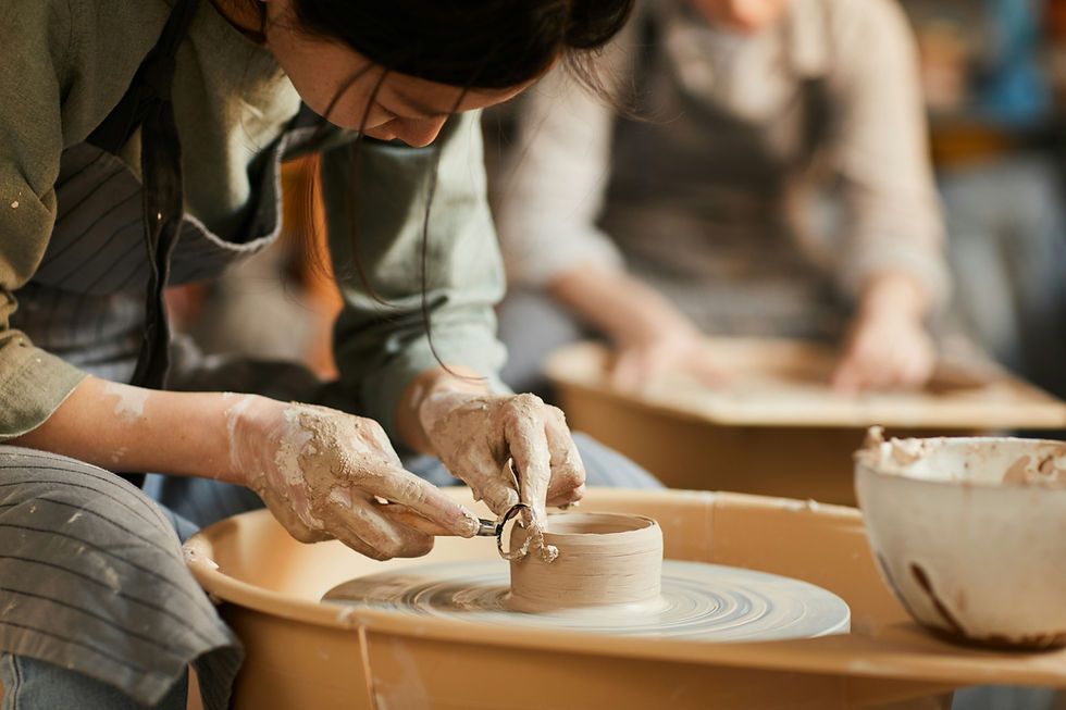 Man and woman laugh happily while working together with clay at a pottery wheel