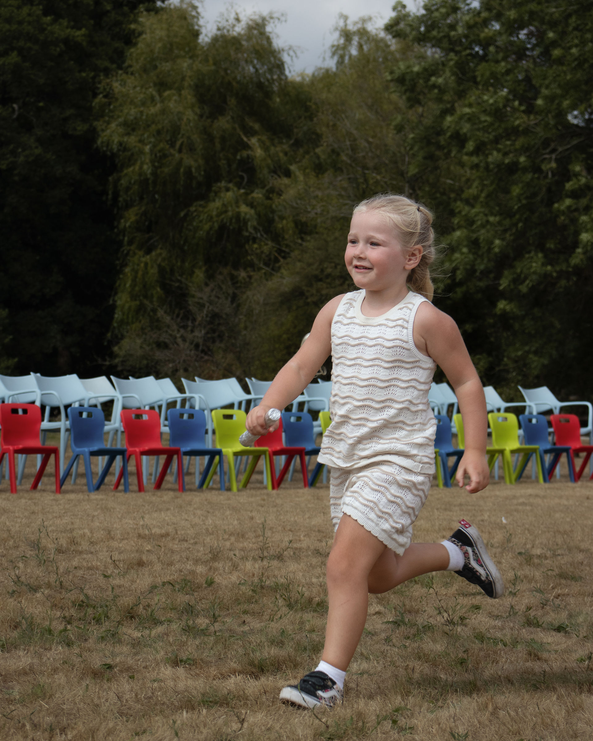 Happy child in white and cream outfit enjoying sports day races at Jubilee Nursery - celebrating confidence and achievement