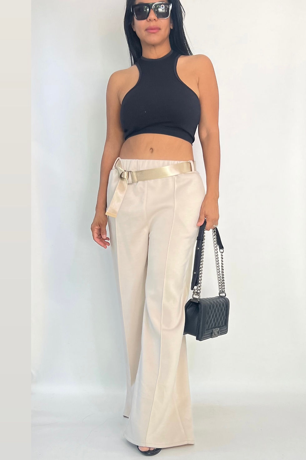 Miniatura: Model in black halter crop top and high-waisted beige trousers