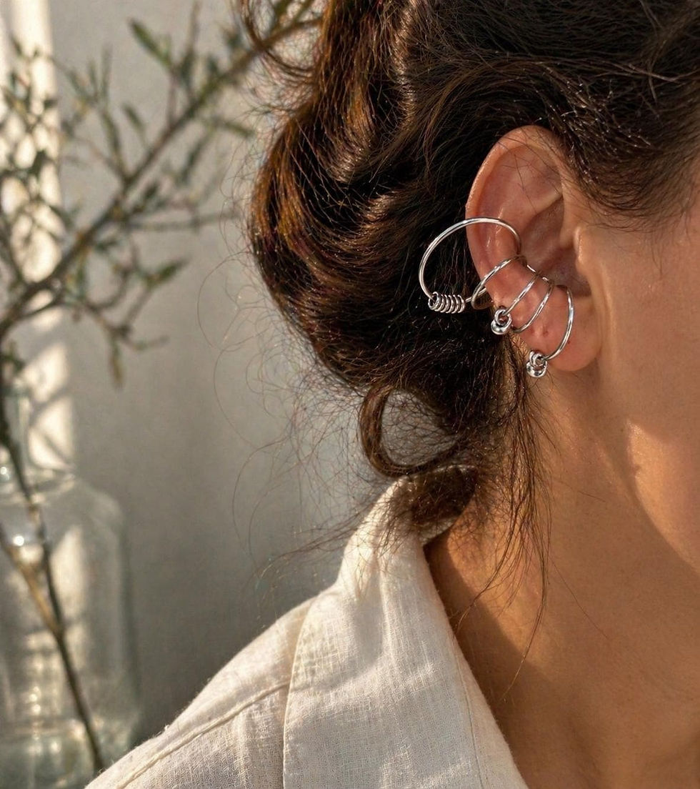 Silver spiral wire ear cuff wrapped across the ear in warm sunlight