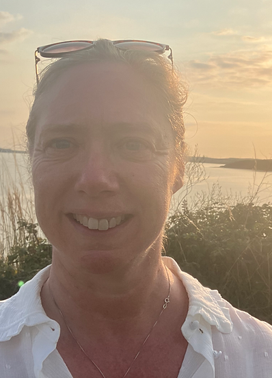Vicky with the sea and the sun setting behind her.