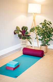 Yoga studio set up with yoga mat, bolster, bricks and block.