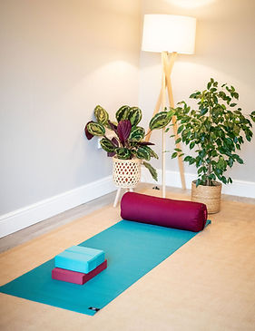 Yoga studio set up with yoga mat, bolster, bricks and block.